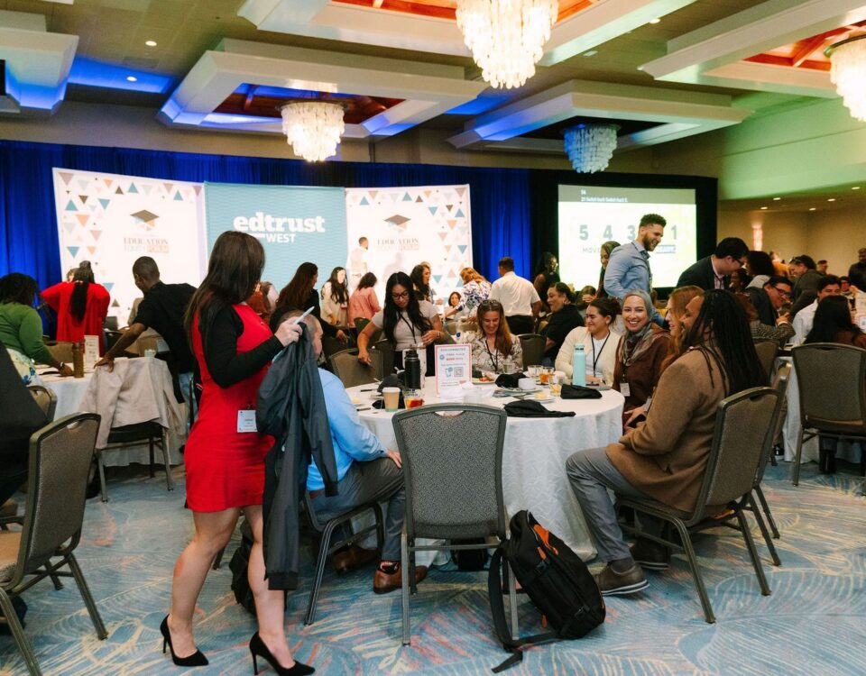 Attendees seated at round tables in the ballroom at the EdTrust-West Education Equity Forum, with the EdTrust-West stage backdrop in the background