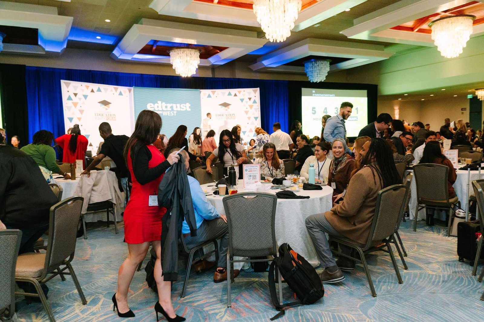 Attendees seated at round tables in the ballroom at the EdTrust-West Education Equity Forum, with the EdTrust-West stage backdrop in the background